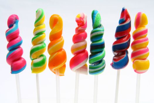 seven rainbow colored lollipop twirl candy isolated in white background
