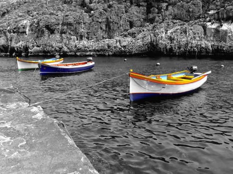 Moored boats in calm ocean waters, in a valley in Malta