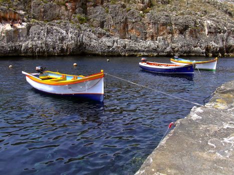 Moored boats in calm ocean waters, in a valley in Malta