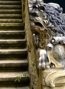 Imposing medieval stone sculpture of lion, guarding palace staircase.