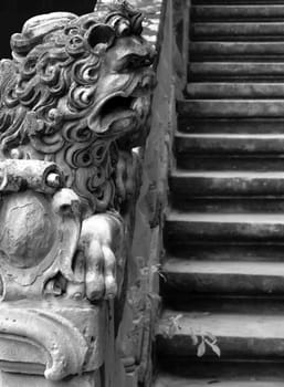 Imposing medieval stone sculpture of lion, guarding palace staircase.