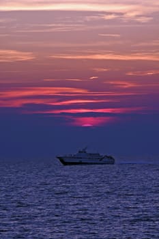 Boat at sunset sailing under sun