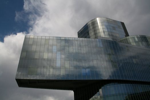 Business building, blue glass, clouded sky background