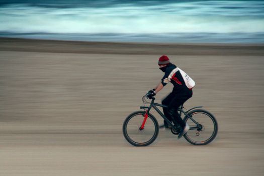 a boy on his bicycle on the beach spinning fast
