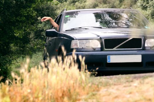 a girl travelling with her arm out of the window's car
