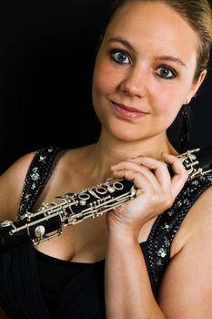 Young beautiful clarinetist woman on black background