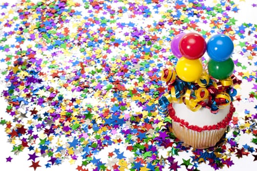 Decorated cupcake with balloons and ribbon with confetti at party.