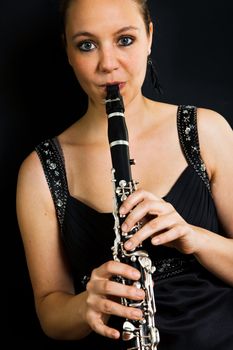 Young beautiful clarinetist playing. Shot on black background