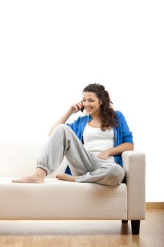 Portrait of a girl seated on the couch and making a phone call