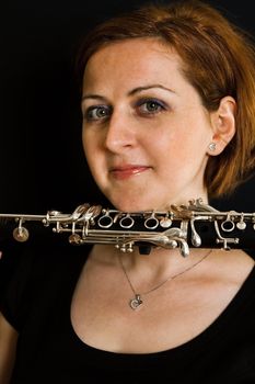 Portrait of beautiful clarinetist women on black background