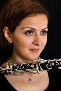 Portrait of beautiful clarinetist women on black background