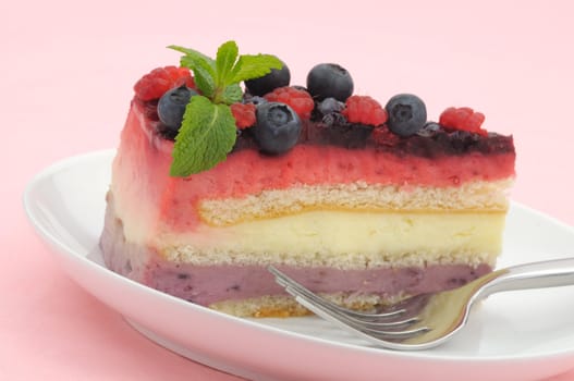 Raspberry and blueberry layer cake slice decorated with mint leaves and fruits