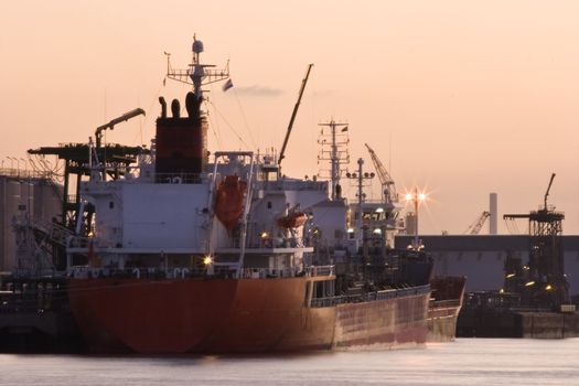 Tankers in port with a red sunrise on the river in autumn