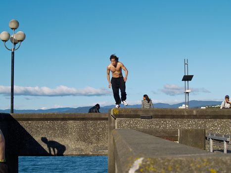 A parkour or free running, building jumping your man, bare chested, practices on the Wellington waterfront.