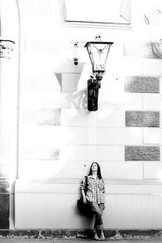 Girl standing near wall under lamp
