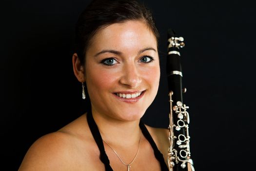 Cheerful clarinetist women posing on black background
