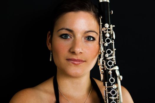 Portrait of beautiful clarinetist women on black background