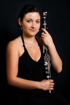 Portrait of beautiful clarinetist women. Portrait on black background