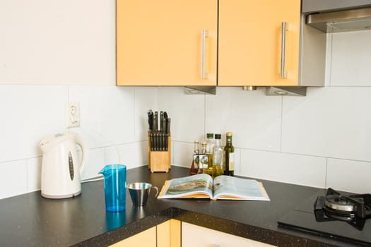 Cooking in colorful modern kitchen with cookbook and other