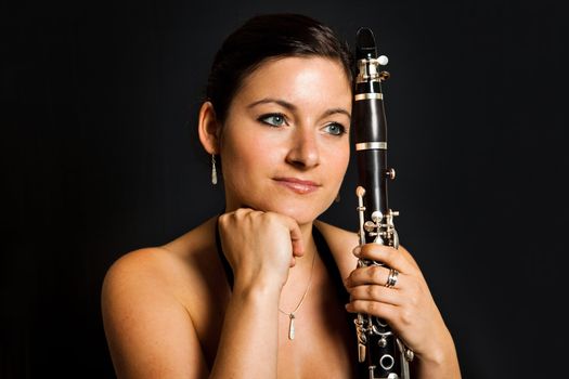 Portrait of beautiful clarinetist women. Portrait on black background