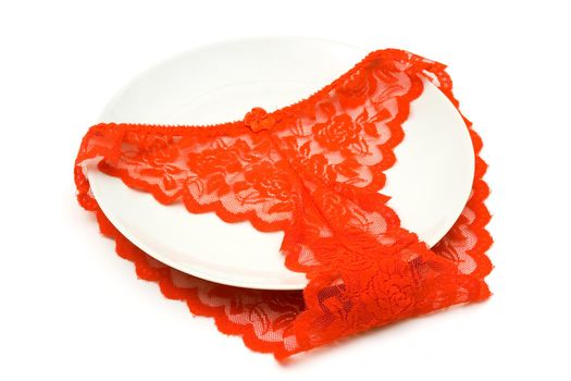 Red Women's elegant and sexy panties, lying on a white dish

