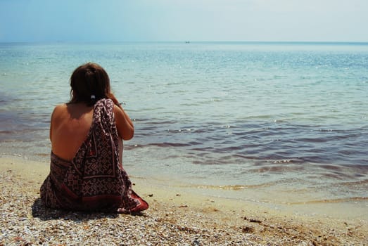 girl sitting on the sand and watching the horizon