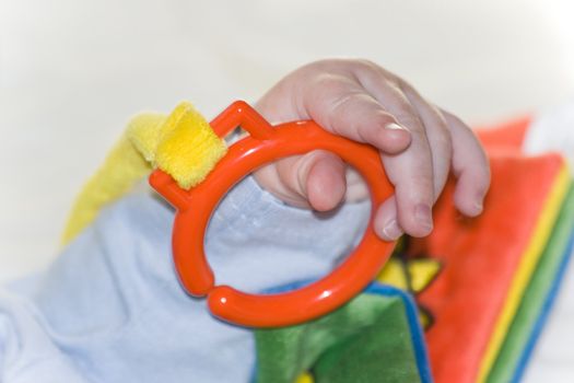 Hand from five months old baby playing with colorful book made from fabric - horizontal