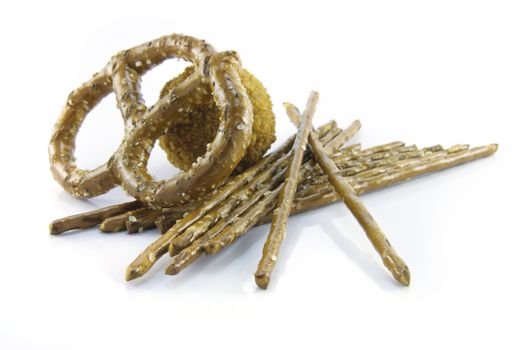 Small tasty scotch egg with salty pretzel sticks and single pretzel  on a reflective white background