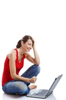 Beautiful and happy young woman sitting on floor and working on a laptop