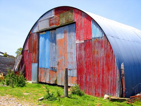 Round Metal Shed on Farm with Mismatched Paint on front surface.