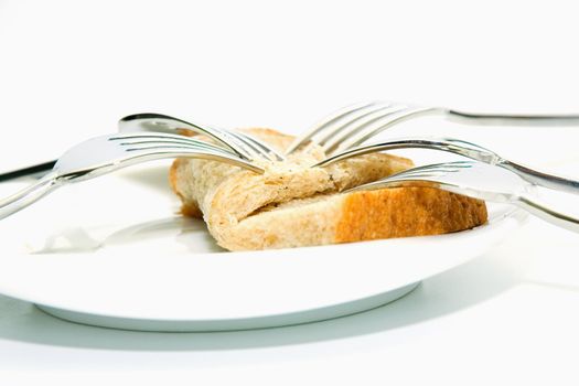 Some forks, white plateau and bread slice on a white background.  The concept of limitation of resources.
The concept  sharing between consumers.
