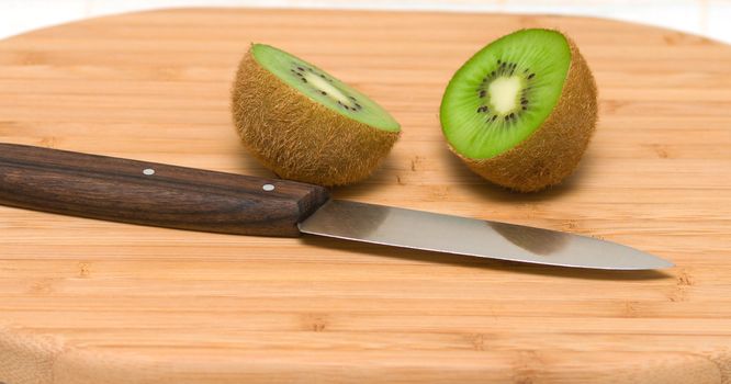 Two halves kiwi on a chopping board.