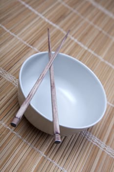 Closeup of chopsticks resting on a bowl