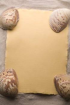 Old yellow paper and shell on sand