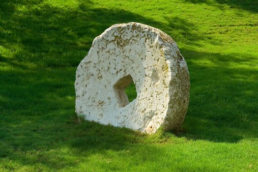 An ancient millstone were located on the grass in the natural background