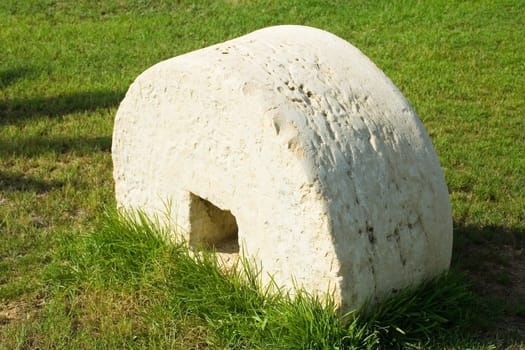 An ancient millstone were located on the grass in the natural background