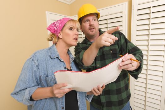 Male Contractor in Hard Hat Discussing Plans with Woman in Room.