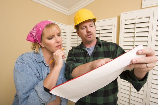 Male Contractor in Hard Hat Discussing Plans with Woman in Room.