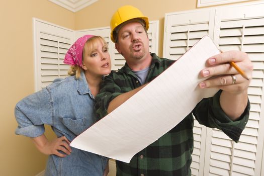 Male Contractor in Hard Hat Discussing Plans with Woman in Room.