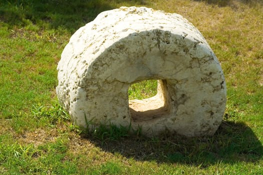 An ancient millstone were located on the grass in the natural background