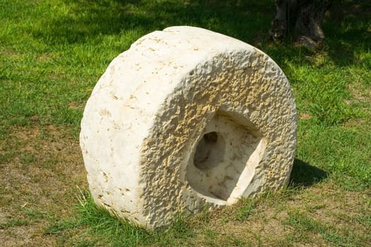 An ancient millstone were located on the grass in the natural background