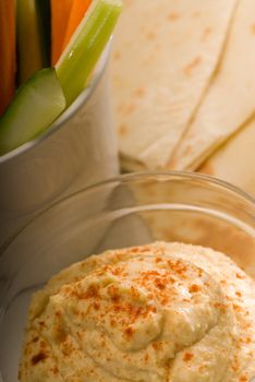 middle eastern hummus dip on a glass bowl with homemade pita brad and raw vegetable