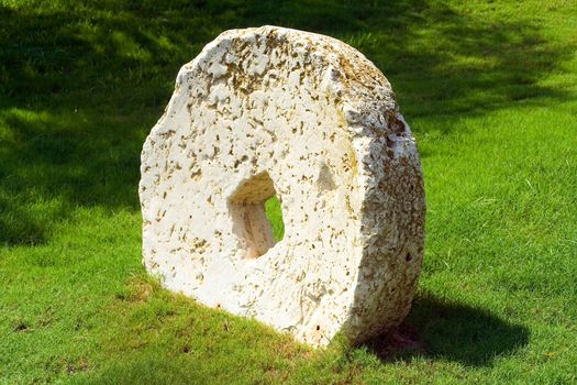 An ancient millstone were located on the grass in the natural background