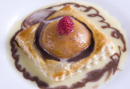 A puff pastry peach on a plate with cream 