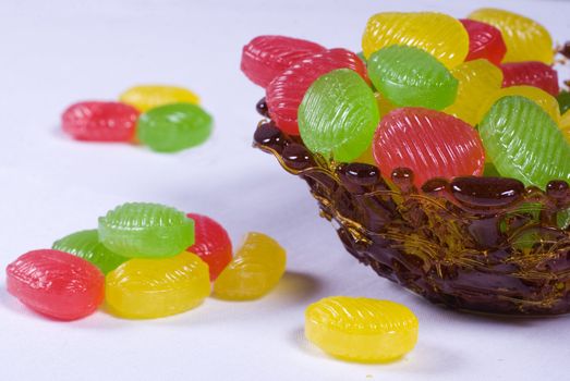 Caramel vase with colored candy on a white background