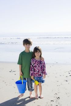 Brother and Sister with Bucket Standing on the Beach