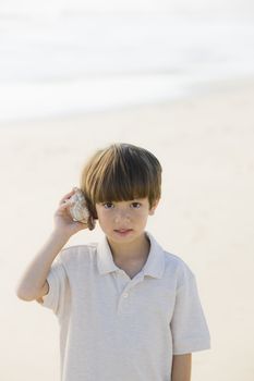 Portrait of a Little Boy Standing at The Beach Listening To A Shell