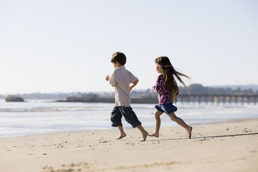 Two Kids Running Barefoot on the Sand at The Beach