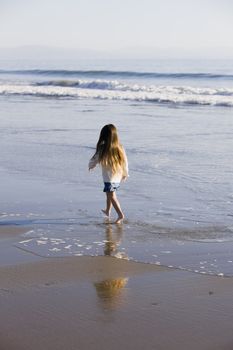 Little Girl Walking in The Water at The Beach