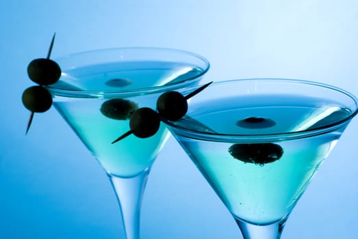 Martini cocktail with olives and blue background